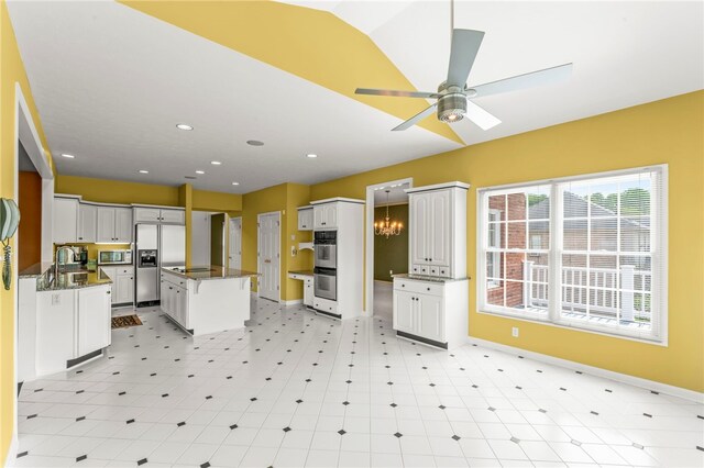 kitchen with stainless steel appliances, a ceiling fan, baseboards, light floors, and white cabinetry