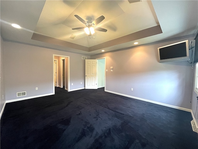 unfurnished bedroom with a raised ceiling, baseboards, dark colored carpet, recessed lighting, and a ceiling fan