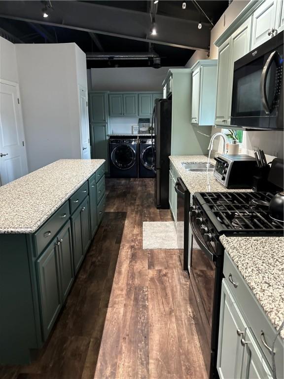 kitchen featuring black appliances, washer and dryer, a sink, a kitchen island, and dark wood-style floors