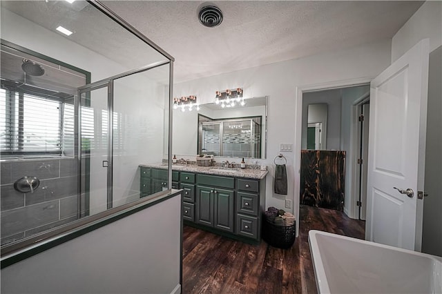 bathroom with wood finished floors, a stall shower, vanity, a textured ceiling, and a soaking tub