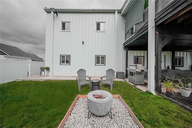 rear view of house featuring a patio area, board and batten siding, an outdoor fire pit, and cooling unit
