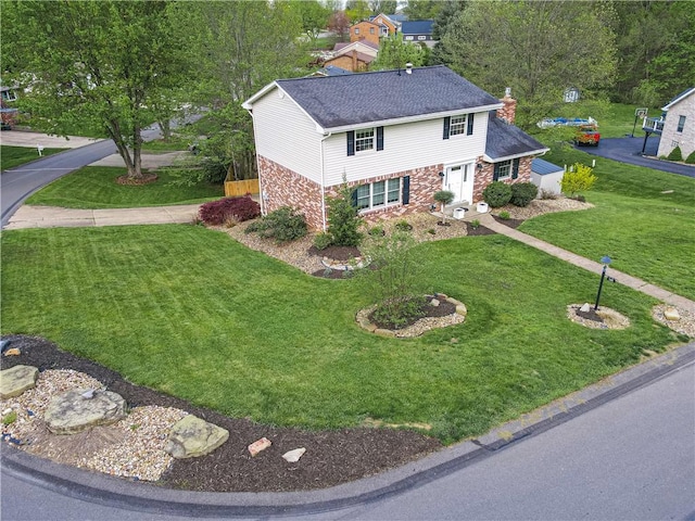 view of front of home featuring brick siding, a chimney, and a front yard