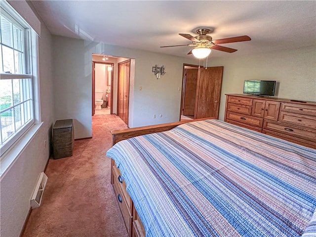 bedroom with light colored carpet, multiple windows, a ceiling fan, and ensuite bath