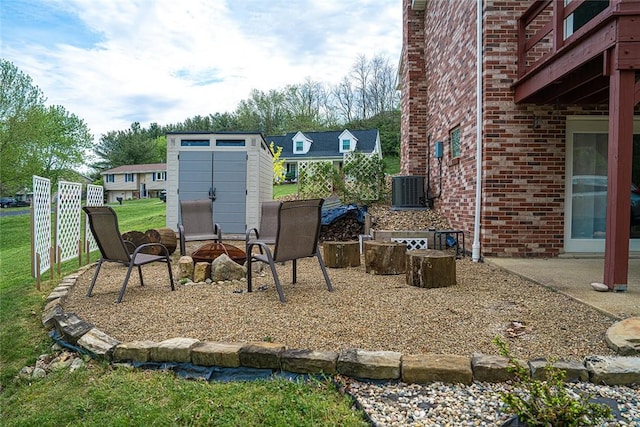 view of patio / terrace featuring a storage unit, an outbuilding, central air condition unit, and an outdoor fire pit