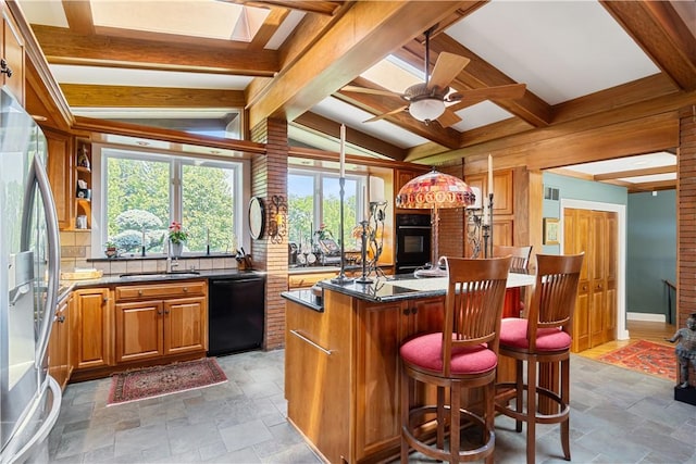 kitchen with black appliances, a sink, stone tile flooring, and a center island