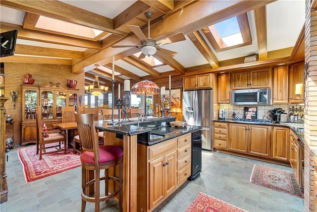 kitchen with appliances with stainless steel finishes, stone tile flooring, a ceiling fan, and backsplash