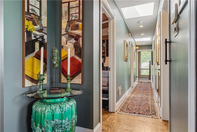 hall with a skylight and baseboards