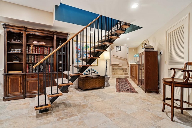 staircase featuring baseboards, stone finish floors, and recessed lighting