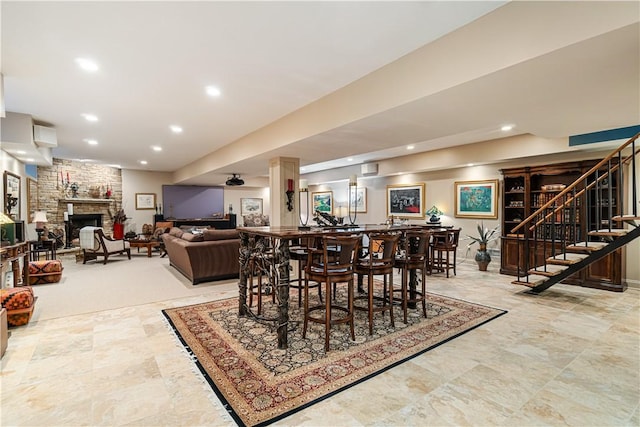 dining room with bar area, stairway, a stone fireplace, and recessed lighting