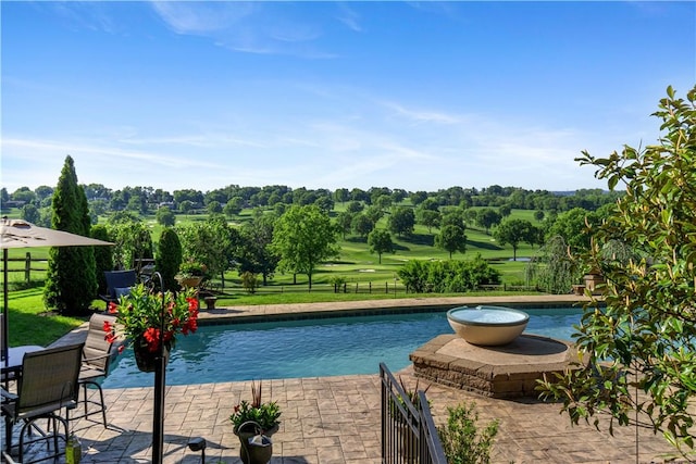 swimming pool with fence, a patio area, and view of wooded area