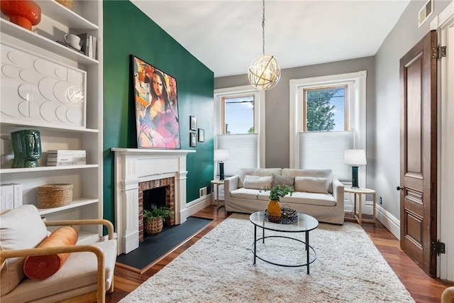 526 Armandale St, Central North Side, PA 15212 - living room featuring wood finished floors, a brick fireplace, baseboards, and a chandelier