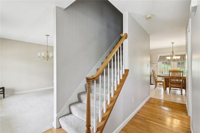 staircase with a chandelier, baseboards, and wood finished floors