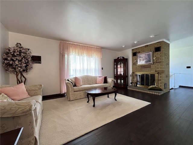 living area featuring baseboards, wood finished floors, and a brick fireplace