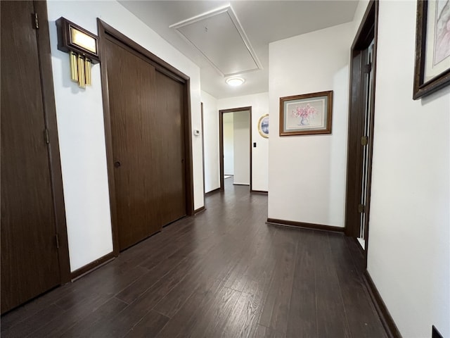 hall featuring attic access, dark wood finished floors, and baseboards