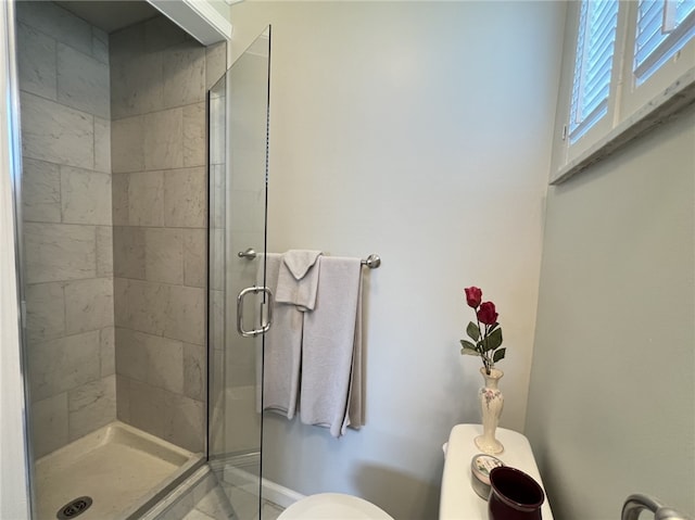 bathroom featuring toilet, a stall shower, and baseboards