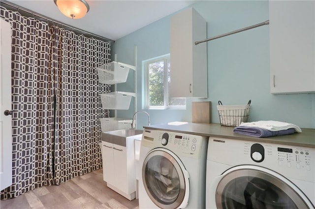 washroom with washing machine and clothes dryer, cabinet space, and light wood-style floors