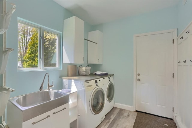 laundry area with cabinet space, washing machine and clothes dryer, light wood finished floors, and baseboards