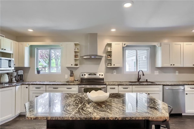 kitchen with wall chimney range hood, appliances with stainless steel finishes, a sink, open shelves, and white cabinetry