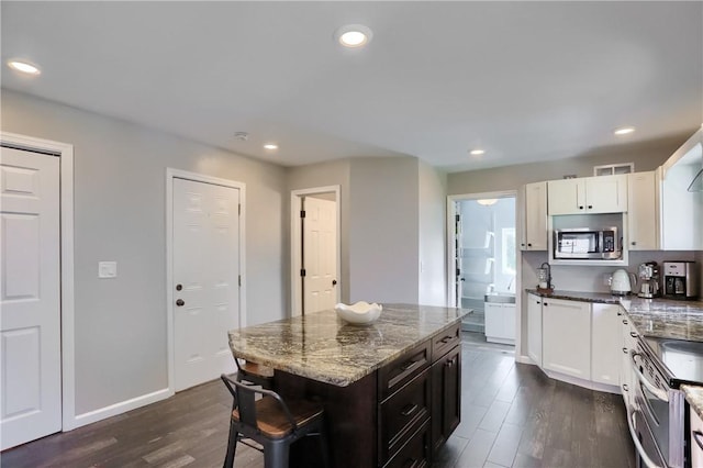 kitchen with appliances with stainless steel finishes, dark wood finished floors, dark stone countertops, white cabinets, and recessed lighting