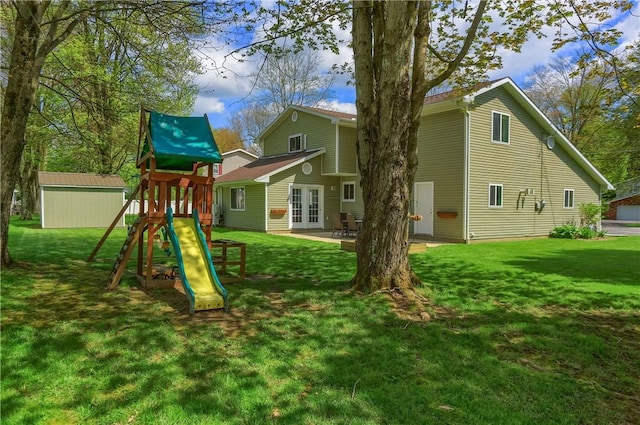 back of property with french doors, a playground, a lawn, and an outbuilding