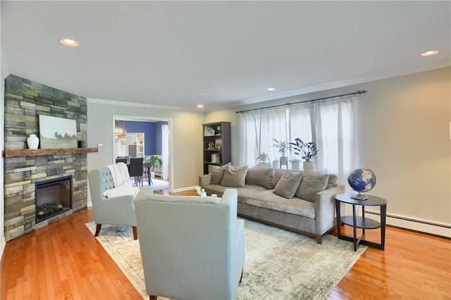living area with crown molding, a stone fireplace, baseboard heating, wood finished floors, and recessed lighting