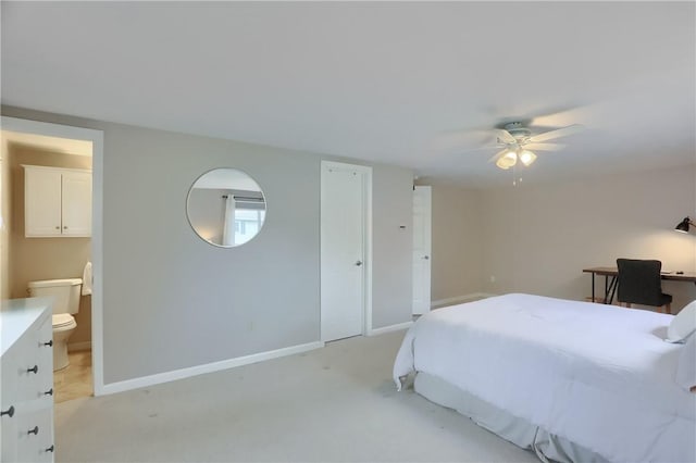 bedroom with light colored carpet, ensuite bathroom, baseboards, and a ceiling fan