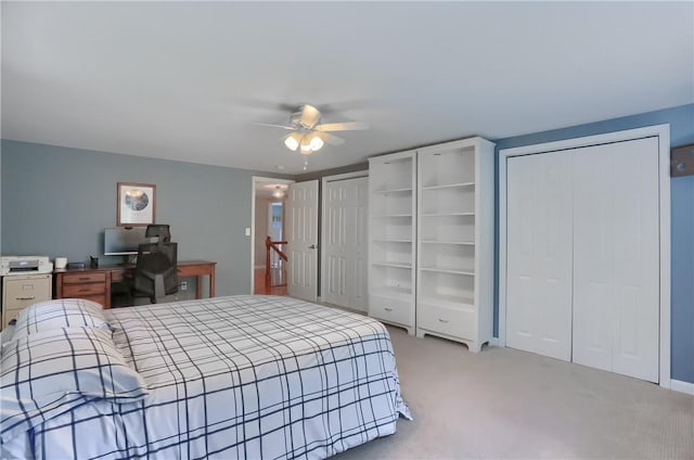 bedroom featuring two closets, light carpet, ceiling fan, and a desk