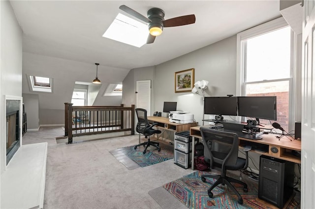 office space with a skylight, a ceiling fan, and light colored carpet