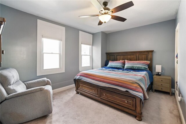 bedroom with light colored carpet, baseboards, and ceiling fan
