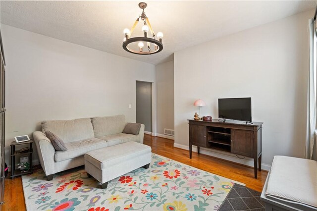 living room with a chandelier, wood finished floors, and baseboards