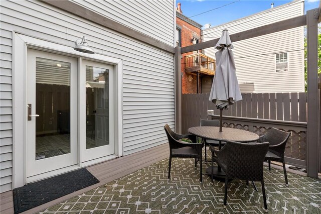 view of patio / terrace featuring fence, a balcony, and outdoor dining area