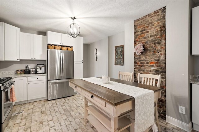 kitchen with stainless steel appliances, white cabinetry, decorative light fixtures, and a textured ceiling