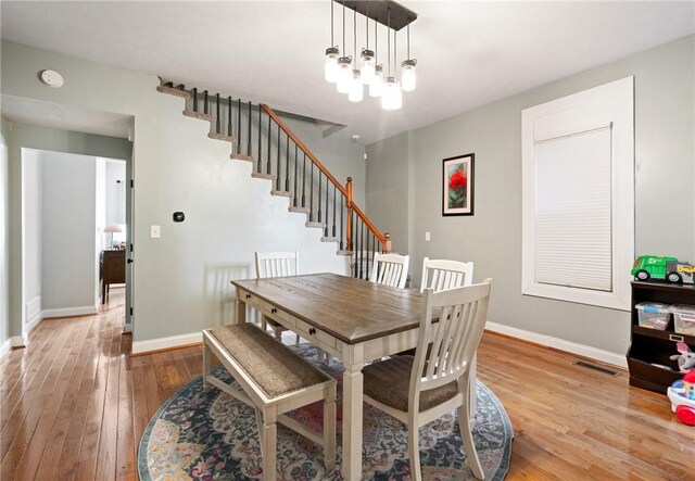 dining room featuring hardwood / wood-style floors, baseboards, and stairway