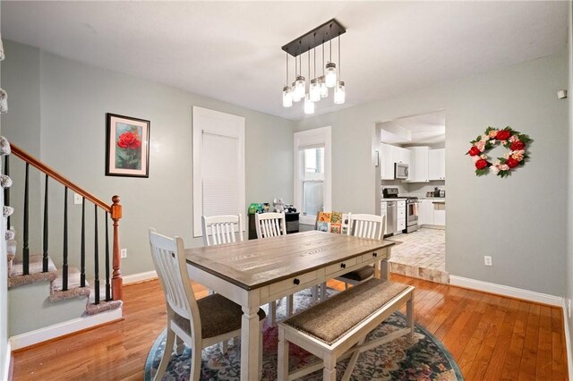 dining space with light wood-style flooring, baseboards, and stairway