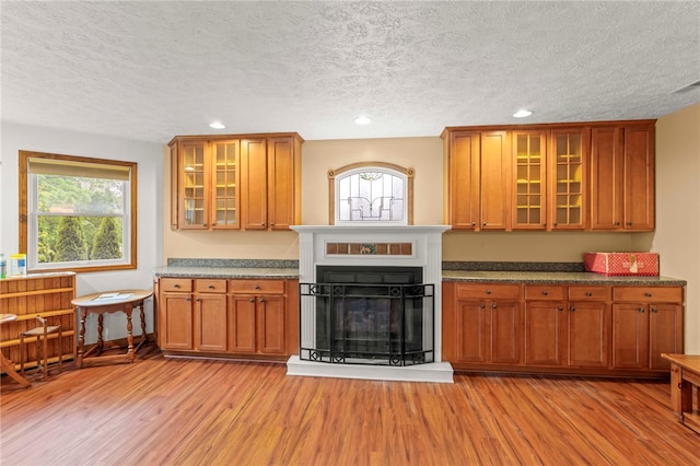 128 Evergreen Dr, Peters Twp, PA 15317 - kitchen with light wood finished floors, a textured ceiling, brown cabinets, recessed lighting, and glass insert cabinets