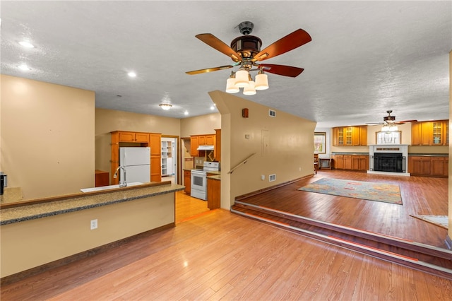 128 Evergreen Dr, Peters Twp, PA 15317 - kitchen with range with electric cooktop, freestanding refrigerator, ceiling fan, brown cabinetry, and under cabinet range hood