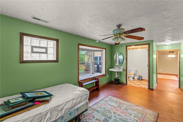 128 Evergreen Dr, Peters Twp, PA 15317 - bedroom with wood finished floors, a textured ceiling, baseboards, and ensuite bathroom
