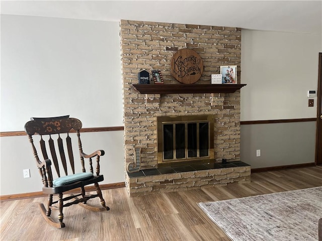 sitting room with wood finished floors, baseboards, and a brick fireplace