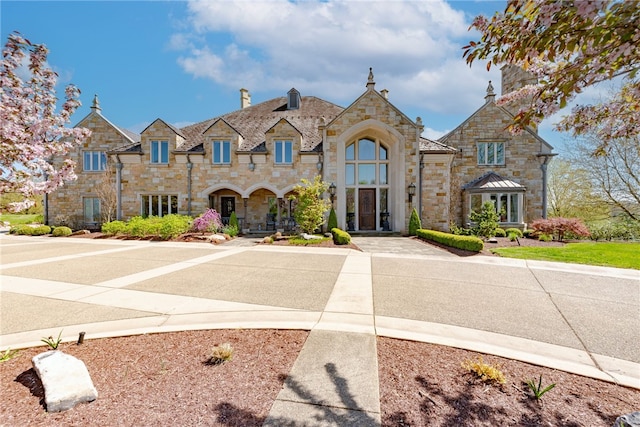 french country inspired facade featuring stone siding and a high end roof