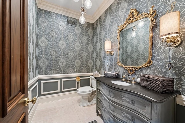 bathroom featuring wallpapered walls, crown molding, toilet, vanity, and a wainscoted wall