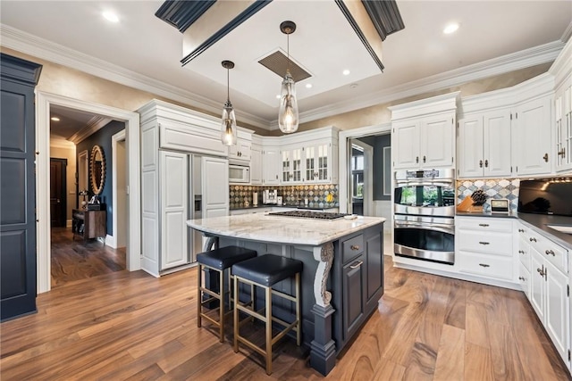 kitchen with built in appliances, white cabinets, backsplash, ornamental molding, and recessed lighting