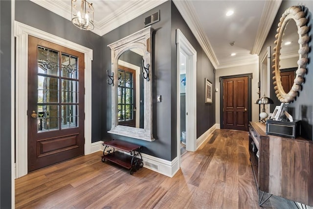 foyer entrance with wood finished floors, a chandelier, baseboards, ornamental molding, and recessed lighting