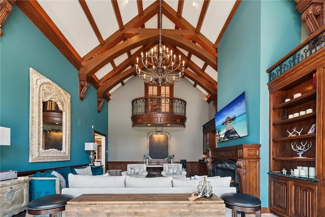 living area featuring high vaulted ceiling, a chandelier, wainscoting, a premium fireplace, and beamed ceiling