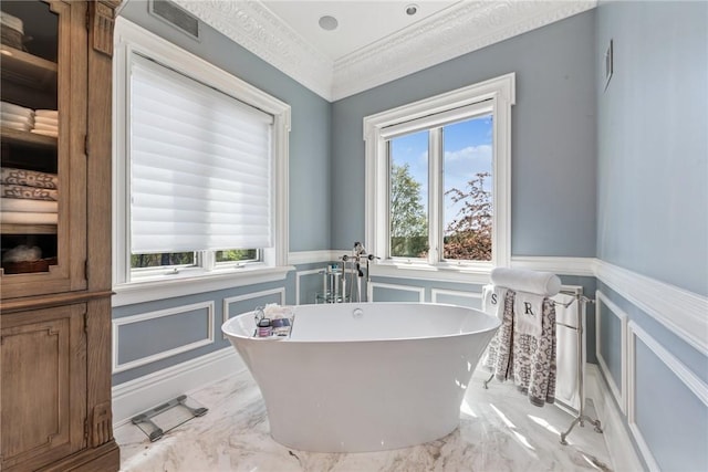 full bathroom featuring marble tiled floors, a wainscoted wall, a decorative wall, a freestanding tub, and ornamental molding