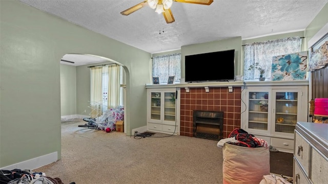 554 Forest Ave, Bellevue, PA 15202 - carpeted living room with arched walkways, a textured ceiling, a ceiling fan, baseboards, and a tiled fireplace