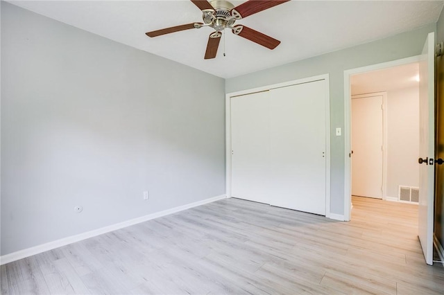 unfurnished bedroom featuring light wood-style floors, a closet, baseboards, and ceiling fan