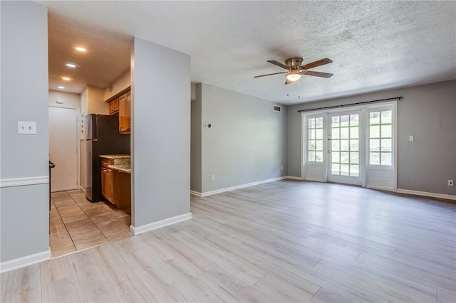 unfurnished living room featuring a ceiling fan, light wood-type flooring, baseboards, a textured ceiling, and recessed lighting