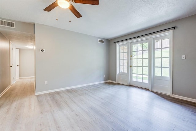 spare room featuring light wood finished floors, ceiling fan, baseboards, and a textured ceiling