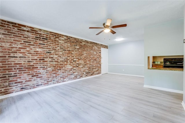 unfurnished living room with baseboards, brick wall, a ceiling fan, and wood finished floors