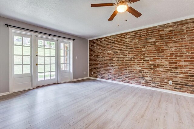 unfurnished room with baseboards, brick wall, wood finished floors, and ceiling fan
